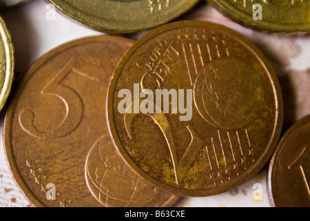 A two Euro cent piece sits atop a five Euro cent piece with other coins also visible Stock Photo