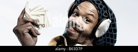 Portrait of a mid adult man listening to music and holding banknotes Stock Photo