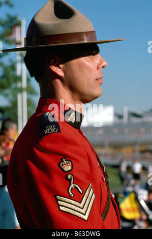 A Canadian Mountie (RCMP) Royal Canadian Mounted Police Officer wearing Traditional Red Serge Uniform and standing at Attention Stock Photo