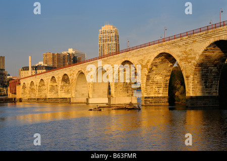 The Stone Arch Bridge reflected in the golden glow of sunrise on the Mississippi river at Minneapolis Minnesota Stock Photo