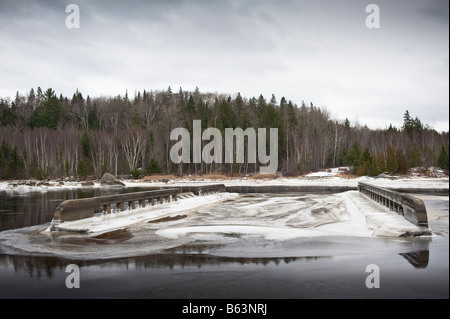 washed out road and bridge from flooding with ice forming on water in new brunswick on st. john river canada Stock Photo