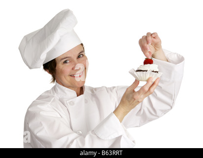 A pastry chef putting a strawberry on the top of a cheesecake tart Isolated on white Stock Photo
