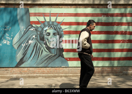 A man passing a painting of the American flag and the statue of Liberty on the outside walls of the Ex US embassy in Tehran Stock Photo