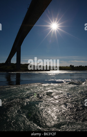 The direct rays of the late evening  sun through the silhouette of the bridge shine across the whirlpools in the Saltstraumen Stock Photo