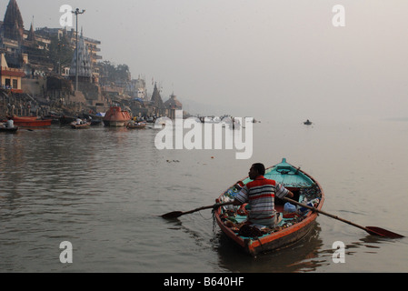 Boat vendor rowing down the river Ganges, Varanasi, India. Stock Photo