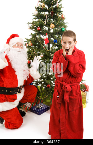 Little boy shocked to discover Santa Claus on Christmas morning Isolated on white Stock Photo