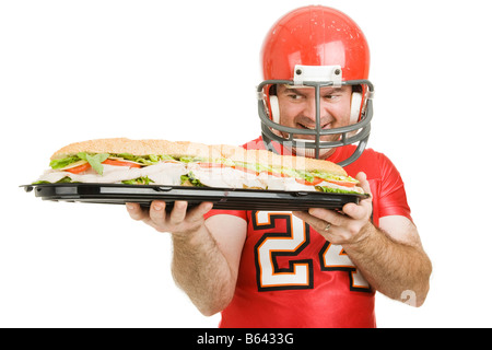 Football player hungrily looking at a giant submarine sandwich Isolated on white Stock Photo