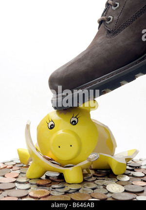 A STARTLED PIGGYBANK BROKEN BY A MANS BOOT SPILLING OUT BRITISH COINS. Stock Photo