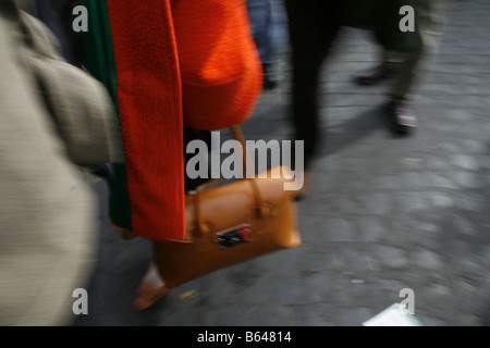 woman with brown leather bag walking in town Stock Photo