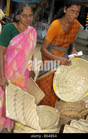 Two Indian woman in saris examining woven baskets to buy Kerala India Stock Photo