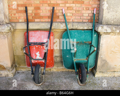 Two wheelbarrows against brick wall Stock Photo