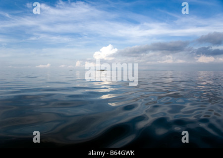 Water level view of Lake Kivu in Rwanda on a cloudy day with cutout fishermen boats on the horizon Stock Photo