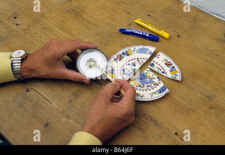 Mending broken saucer with Araldite. Stock Photo