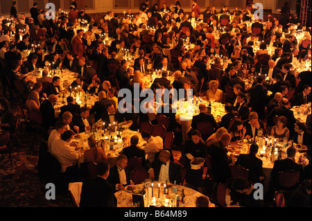 Large group of people seated at tables at evening business formal black tie event. Smart gala dinner, elevated view. Stock Photo