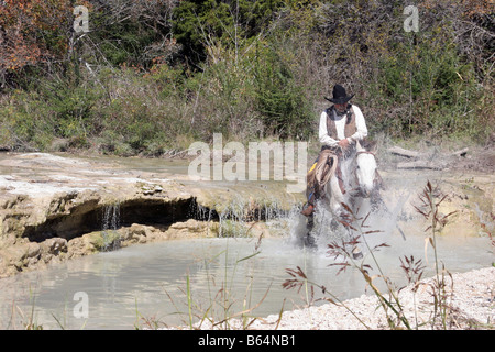 A cowboy and horse crossing a stream in Texas Stock Photo