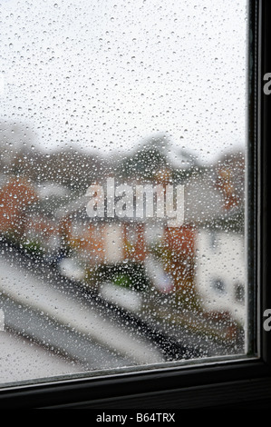 A row of houses seen through raindrops on a window during a rain storm on a dull grey day Stock Photo