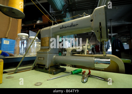 One of many old sewing machines and workspaces for seamstresses or tailors in a dry cleaning and alternations shop Stock Photo