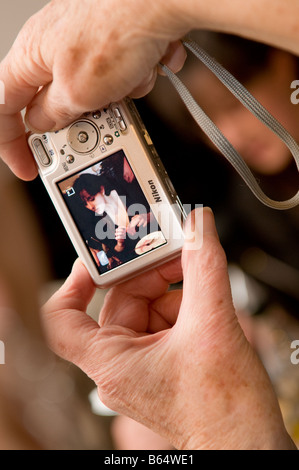 close up detail of the hands of an elderly person taking a photograph of young woman on her compact digital camera.UK Stock Photo