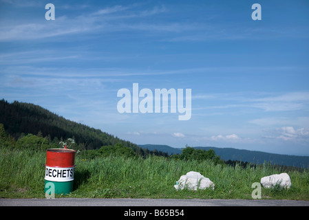 Garbage can on side of road overlooking rolling landscape Stock Photo