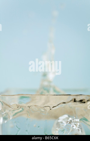 Water splashing from ice-cube dropped into glass of water, extreme close-up Stock Photo