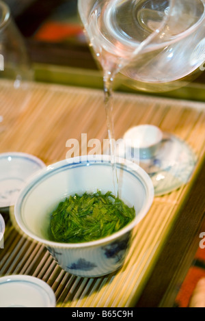 Hot water poured from glass teapot over tea leaves in gaiwan cup Stock Photo