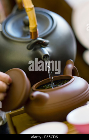 Hot water being poured from kettle into brewing teapot Stock Photo