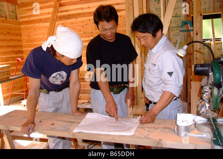 Three Japanese carpenters looking a blueprint of a house Stock Photo
