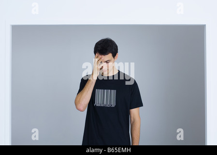 Man wearing tee-shirt printed with bar code, covering face with hand Stock Photo