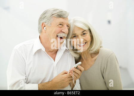 Senior couple listening to MP3 player together, woman smiling at camera Stock Photo