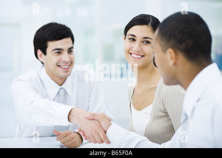 Professionals sitting at table, shaking hands Stock Photo