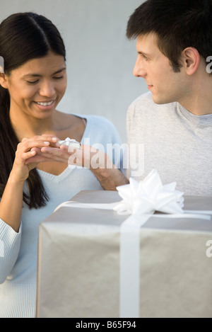 Man giving woman tiny gift, large gift in foreground Stock Photo