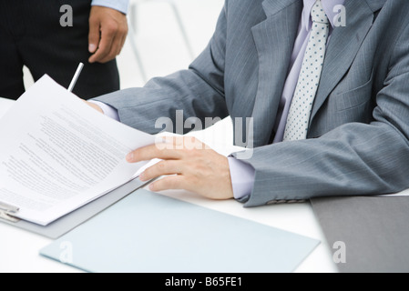 Businessman reviewing document at desk, cropped view Stock Photo