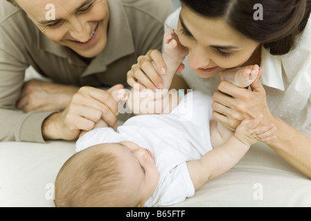 Parents smiling down at baby, mother holding baby's feet, cropped view Stock Photo