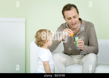 Father and toddler blowing bubbles together Stock Photo
