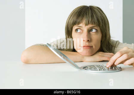 Woman resting head on arms, playing peg solitaire game, looking away Stock Photo