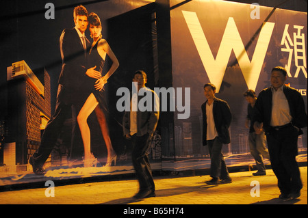 Chinese men walk past a billboard featuring a luxurious hotel being built in Guangzhou,China. 26-Nov-2008 Stock Photo
