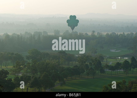 Hot air balloon shaped like a clover hovering over a golf course early on a foggy morning Stock Photo