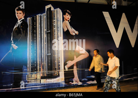 Chinese men walk past a billboard featuring a luxurious hotel being built in Guangzhou,China. 26-Nov-2008 Stock Photo