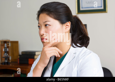 Female Asian Doctor thinking in her office. Stock Photo
