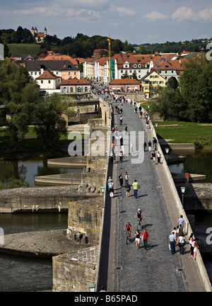 People walking across the old stone bridge built in the Middle Ages across the river Danube Regensburg Germany Stock Photo