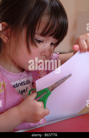 Little girl using scissors to cut out a circle Stock Photo