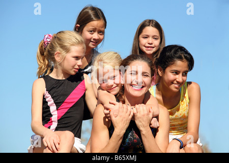 Woman laughing and five girls around her Stock Photo