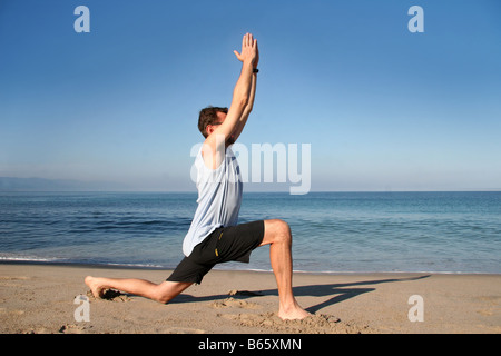 Man doing yoga exercise on the beach Stock Photo
