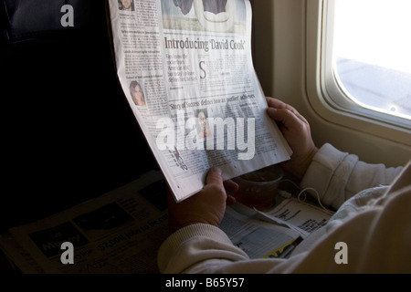 Man reads newspaper on airplane, window seat Stock Photo
