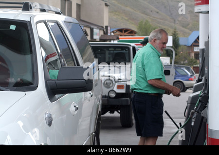 A man at gas station filling up an SUV vehicle Stock Photo