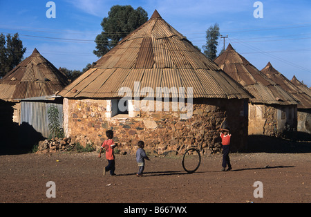 Eritrean boys playing with a hoop or bicycle tyre outside their round house or hut, Asmara, Eritrea Stock Photo