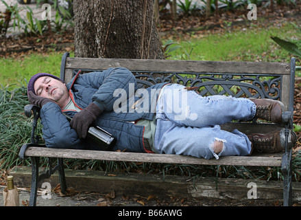 Homeless man on a park bench with a cardboard sign Stock Photo - Alamy