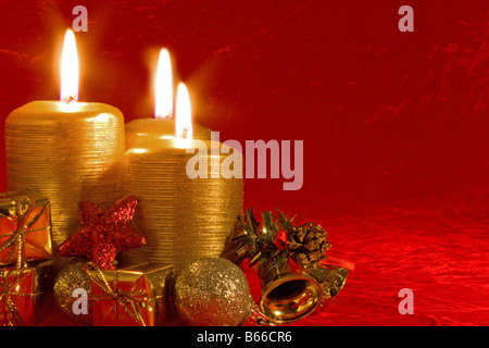 Three burning candles in a Christmas setting with seasonal decorations Stock Photo