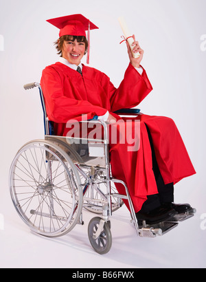 Studio portrait of male graduate in red gown in wheelchair Stock Photo