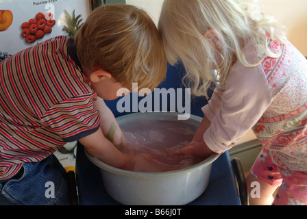 Children washing hands in a washing up bowl Stock Photo